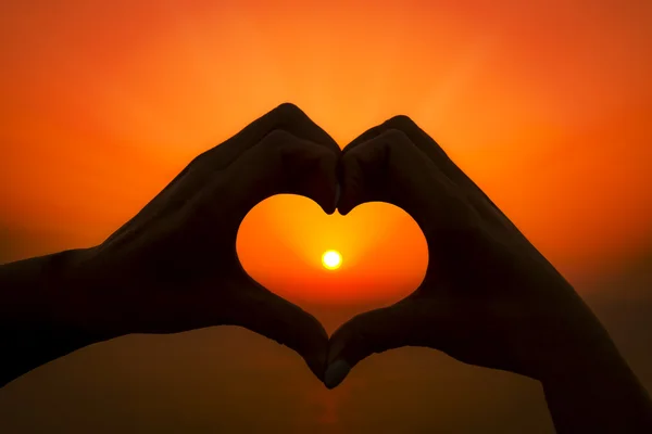 Deux mains font un cœur autour du soleil couchant sur une île grecque — Photo