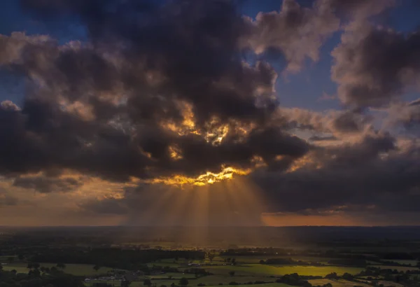 Raios crepusculares de luz solar brilham sobre os campos em Dorset — Fotografia de Stock