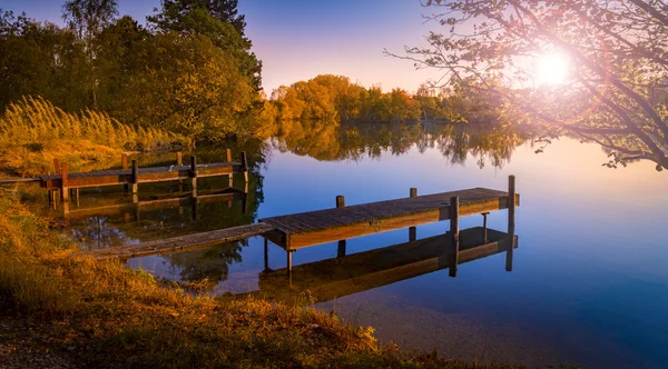 Jetty de madeira em um lago Becalmed ao pôr do sol — Fotografia de Stock