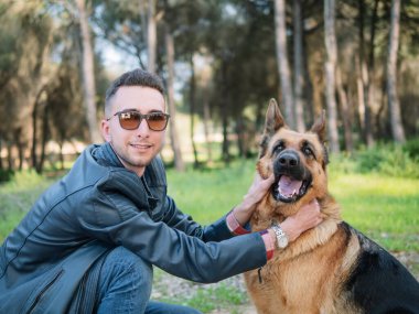 Genç adam ormanda köpeğiyle oynuyor. Seçici odak