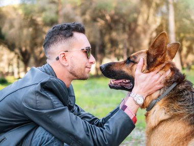 Genç adam ormanda köpeğiyle oynuyor. Seçici odak