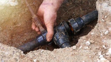 Çiftçi elleri sulama için tarladaki boruları tamir ediyor. Seçici odak.