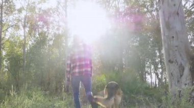 Genç adam ormanda köpeğiyle yürüyor. Seçici odak