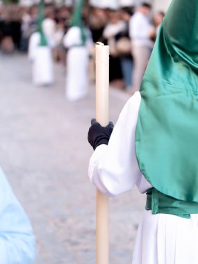 İspanyol caddesindeki geleneksel dini geçit töreninde elinde büyük bir mum tutan yeşil başlık ve beyaz bir tunik giyen bir tövbekâr.