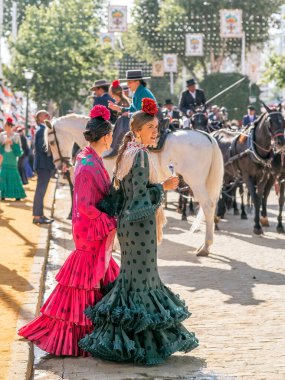 Seville, İspanya - 06 Mayıs 2025: Sevilla Fuarı 'nda renkli flamenko elbiseli kadınlar.