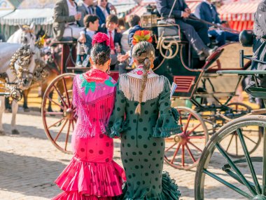 Seville, İspanya - 06 Mayıs 2025: Sevilla Fuarı 'nda renkli flamenko elbiseli kadınlar.