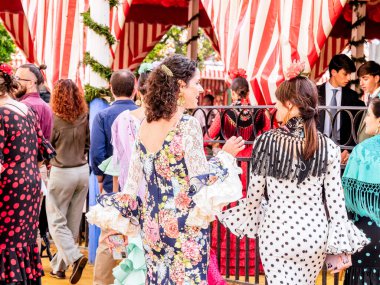 Seville, İspanya - 06 Mayıs 2025: Sevilla Fuarı 'nda renkli flamenko elbiseli kadınlar.