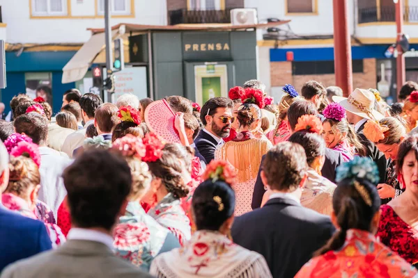 Seville, İspanya - 06 Mayıs 2025: Fuar sırasında bir şehir caddesinde Flamenko elbiseler ve takım elbiseler giymiş bir kalabalığın arka planı.