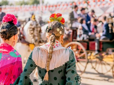 Seville, İspanya - 06 Mayıs 2025: Sevilla Fuarı 'nda renkli flamenko elbiseli kadınlar.