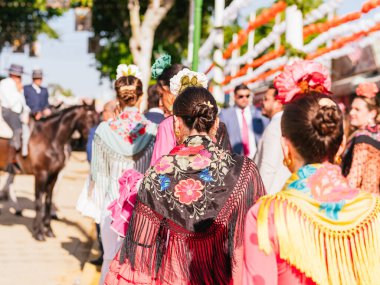 Seville, İspanya - 06 Mayıs 2025: Sevilla Fuarı 'nda renkli flamenko elbiseli kadınlar.