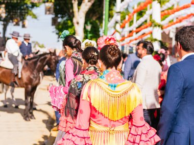 Seville, İspanya - 06 Mayıs 2025: Sevilla Fuarı 'nda renkli flamenko elbiseli kadınlar.