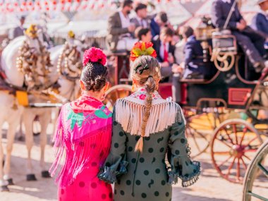 Seville, İspanya - 06 Mayıs 2025: Sevilla Fuarı 'nda renkli flamenko elbiseli kadınlar.