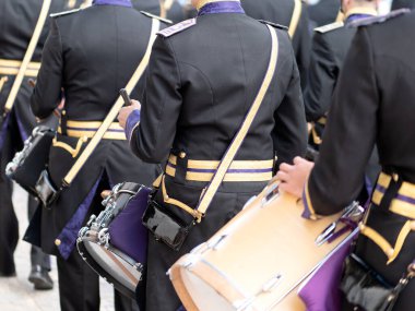 İspanya 'da geleneksel bir Kutsal Hafta geçit töreninde yürürken siyah ve altın üniformalı müzisyenlerin arkasından yaklaş..