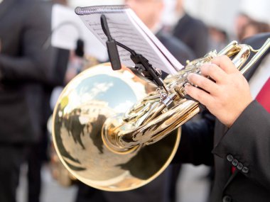 İspanyol şehrinde düzenlenen geleneksel festival geçit töreninde, siyah takım elbiseli bir müzisyenin Fransız kornosu çalmasının detaylı görüntüsü..