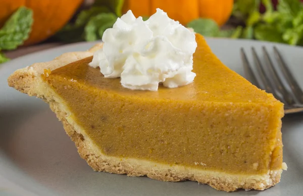 Fetta di torta di zucca su un piatto con panna montata — Foto Stock