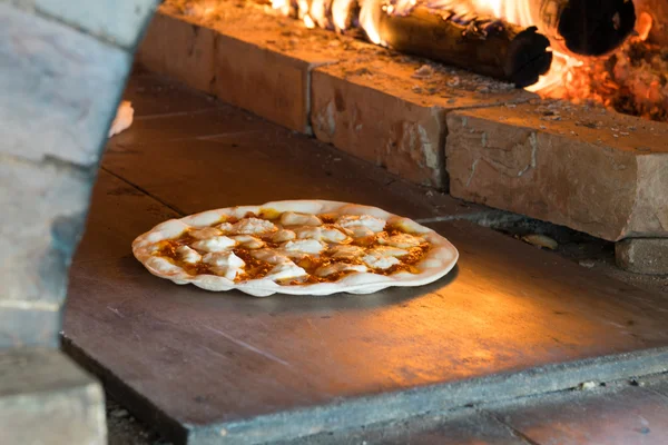 Thin crust pizza baking in wood fired oven