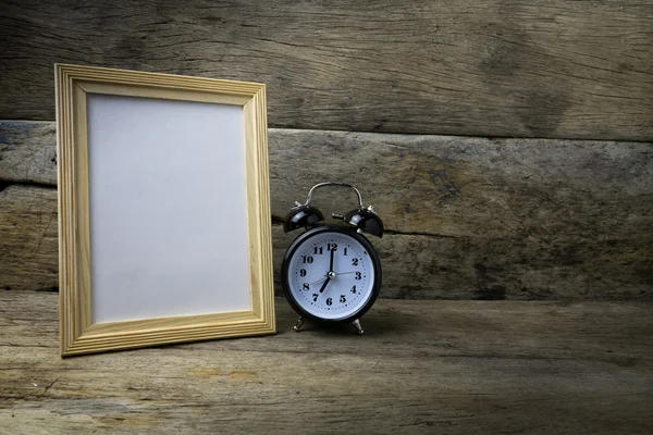 Houten fotolijst en klok op houten tafel — Stockfoto