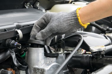 Tamirci bir otomobil motorundan yağ kapağı açıyor.