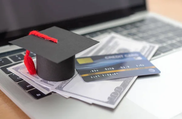 Credit card, Academic hat model and Notebook on wooden desk. Online payment by using laptop