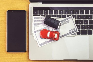 Araba modelinin yanındaki akıllı telefon, para ve tahta masanın üzerindeki defter. Çevrimiçi alışveriş ve araba ödemesi 