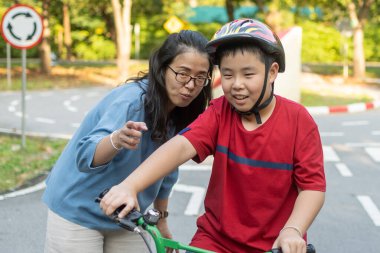 Anne parkta bisiklete binmeyi güneşe öğretiyor. Aile dışarıda bisiklet sürüyor..