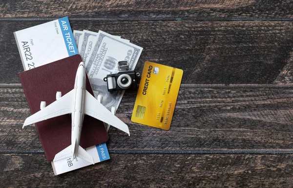 Toy airplane, Air Ticket, credit cards, dollars and passport on wooden table. Travel concept