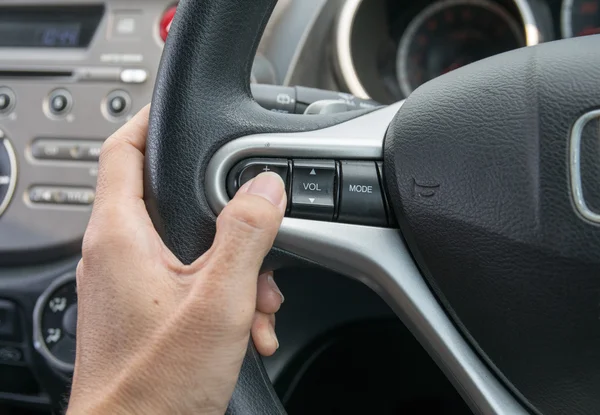 Een hand drukt de cruisecontroleknop op een stuurwiel. — Stockfoto