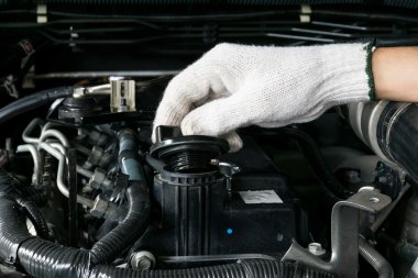 Tamirci bir otomobil motorundan yağ kapağı açıyor.