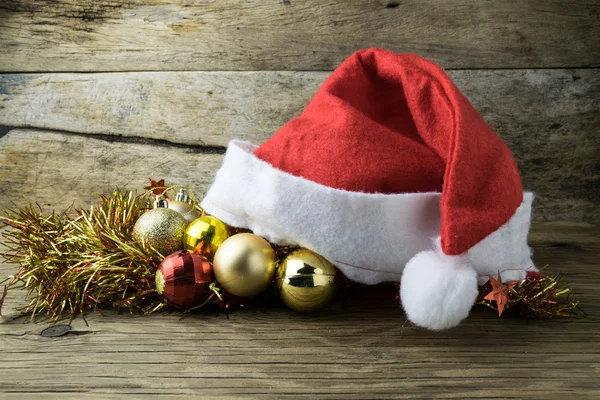 Noel Baba şapkası ile eski ahşap arka plan üzerinde Noel süsleri. — Stok fotoğraf