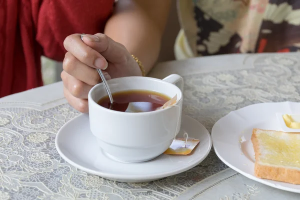 Caneca branca de chá na mão no fundo da mesa — Fotografia de Stock