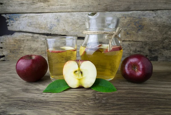 Яблочный сок и яблоки на деревянном столе — стоковое фото