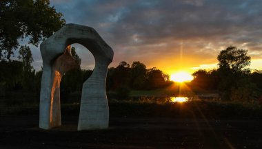 Travertine arch sculpture, and an epic sunset. Autumn trees silhouette. Kensington Gardens, London. clipart