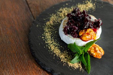 Kızılcık soslu taze pişmiş camembert peyniri, otlar ve karamelli ceviz yakından.