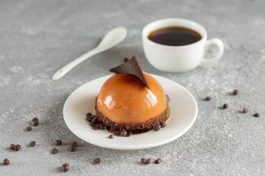 Çikolatalı, yuvarlak kremalı kek ve bir fincan kahve.