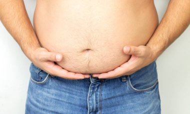 Şişman adam büyük göbeğini sıkı sıkı tutuyor.