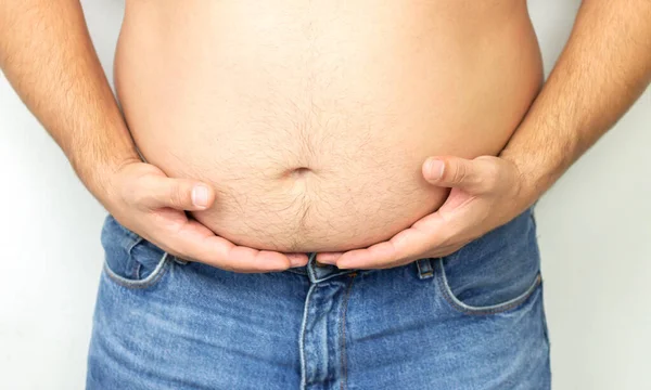 Şişman adam büyük göbeğini sıkı sıkı tutuyor.
