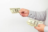 Podnikatel dává peníze nám dolarové bankovky close-up