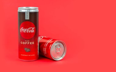 Kiev, Ukrayna - 17 Aralık 2020: İki kutu köpüklü Coca-Cola artı kırmızı arkaplanda kahve özü. Metin için boşluk