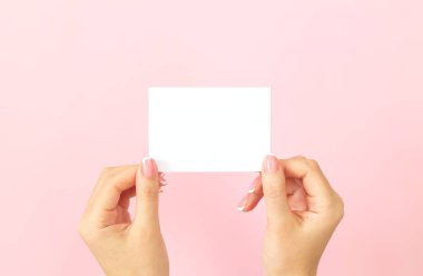 Kadın eli boş beyaz kartvizit tutuyor. İndirim ya da pembe arka planda fotokopi alanı olan broşür. Tasarımınız için şablon