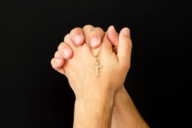 Hıristiyan haçı taşıyan genç erkek elleri kilisede Tanrı 'ya dua ediyor.