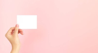 Kadın elinde boş beyaz kartvizit, indirim ya da pembe arka planda fotokopi alanı olan el ilanı tutuyor. Tasarımınız için şablon