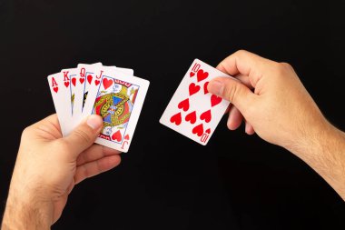 Erkekler, koyu arkaplanda floş poker kartlarının kombinasyonunu tutuyor. Kumarhane, şans ve servet konsepti