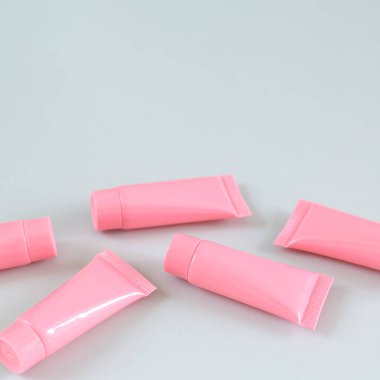 Gri arka planda beş pembe kozmetik tüp yakın plan. Spa ürün kapları tasarımı. Boşluğu kopyala