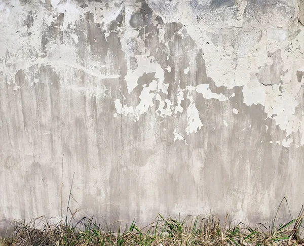 Cracked weathered concrete street wall with green grass background