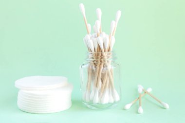 Bambu organik pamuklu çubuklar cam kavanozda ve pamuklu pedler kişisel hijyen manzarası için.