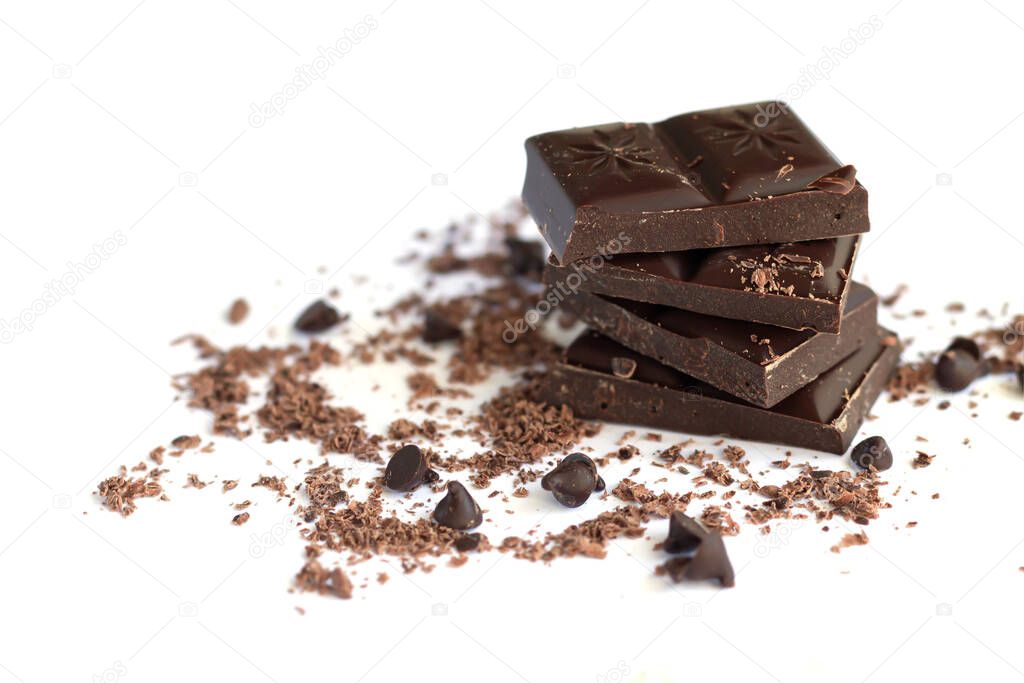 Dark chocolate stack with chocolate flakes, powder and drops isolated on white background