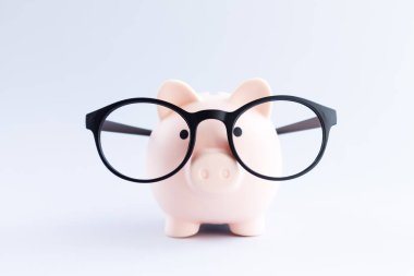Piggybank wear glasses on gray table close-up. Saving money or savings concept