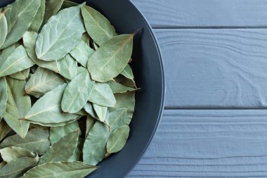 Tahta masa manzaralı karemik kasede kuru defne yaprağı ya da defne.