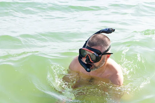 Man with snorkeling equipment: snorkel and scuba mask on the sea water