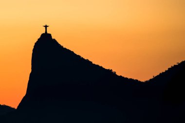 Cristo Redentor gün batımında, turuncu gökyüzü ile, Rio de Janeiro, Brezilya